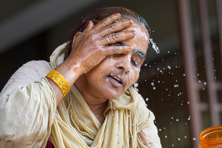 बुधवार, 29 मई, 2024 को नई दिल्ली में भीषण गर्मी के बीच एक महिला अपने चेहरे पर पानी छिड़कती हुई। (स्रोत: पीटीआई)