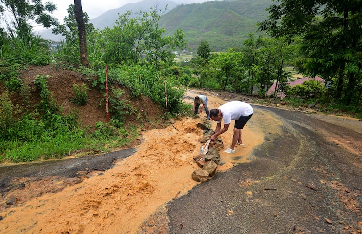 मणिपुर के सेनापति जिले में लगातार बारिश के दौरान सड़क से पानी की निकासी करते निवासी, मंगलवार, 28 मई, 2024. (स्रोत: पीटीआई)