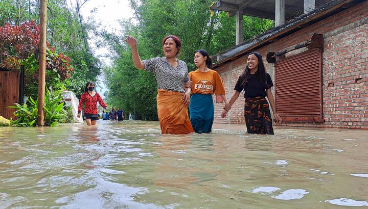 इंफाल में चक्रवात 'रेमल' के आने के बाद हुई बारिश से जलमग्न सड़क से गुजरते लोग। (स्रोत: पीटीआई)