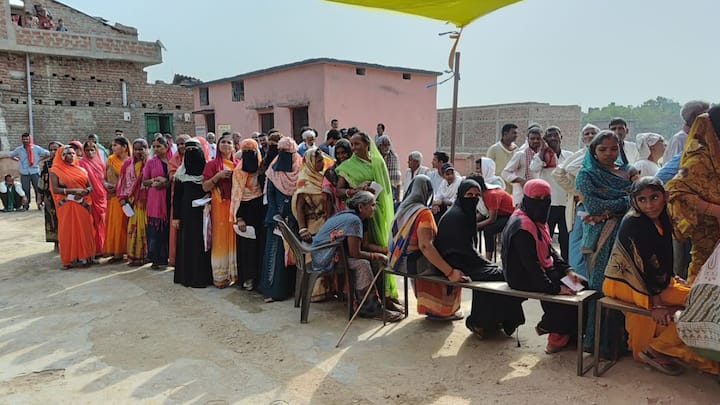 आम चुनाव के अंतिम चरण के दौरान बिहार के एक मतदान केंद्र पर तिरपाल के नीचे शरण लेते लोग। मतदाताओं ने दोपहर की धूप से बचने के लिए सुबह मतदान करने की कोशिश की। (फोटो: @ECISVEEP)