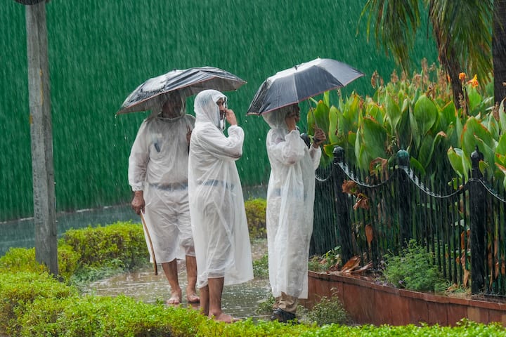 गुरुवार, 27 जून, 2024 को नई दिल्ली में संसद भवन परिसर के पास बारिश के दौरान रेनकोट पहने और छाते लिए सुरक्षाकर्मी निगरानी करते हुए। (छवि स्रोत: पीटीआई)