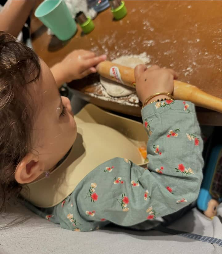 The second photo shows Malti wearing a cute green outfit and making 'roti'.