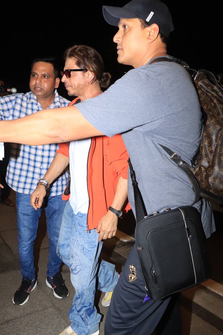 For his airport look, Shah Rukh Khan paired a red jacket over a white T-shirt and wore blue baggy denim.
