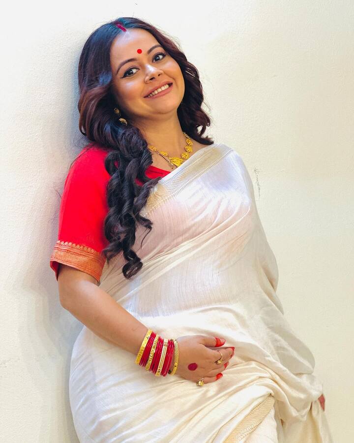 देवोलिना भट्टाचार्जी इन तस्वीरों में व्हाइट साड़ी के साथ रेड ब्लाउज और हैवी मेकअप में नजर आ रही हैं.