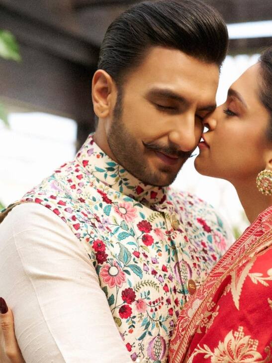 Ranveer Singh looks stunning in a sleeveless jacket with floral patterns and a white shirt. His well-groomed hair, classic beard, and moustache all contribute to his classy vibe.