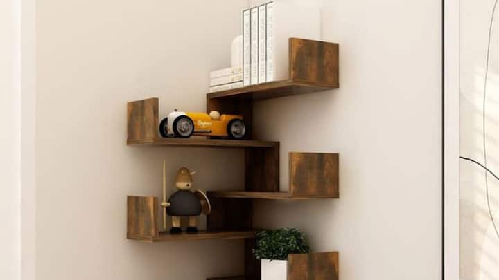 6. Corner Book Shelves To Save Space: If you are an avid reader and have a small apartment space, you may not have the luxury of a conventional bookshelf, then you can go for the wall corner bookshelves. These shelves are specially designed to fit any vacant corner and hence do not occupy any of your floor space for storage purposes. A corner bookshelf makes the living room or bedroom look trendy and doubles up as furniture. You can use this design efficiently, and it can eventually become the centre of attention in a room providing effective space-saving storage while beautifying the entire interior of the room. (Image Source: Pinterest/WayfairUK)