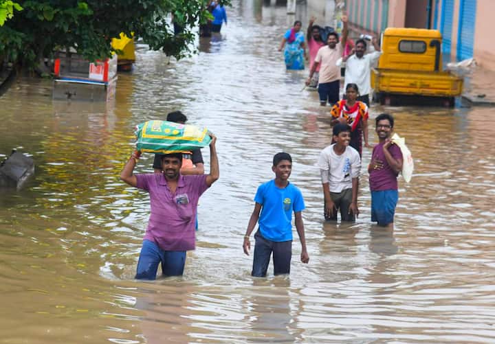 People cross a waterlogged street at the Bhavanipuram Sitara Center flood affected area, in Vijayawada, Monday, Sept. 2, 2024. (Image Source: PTI)