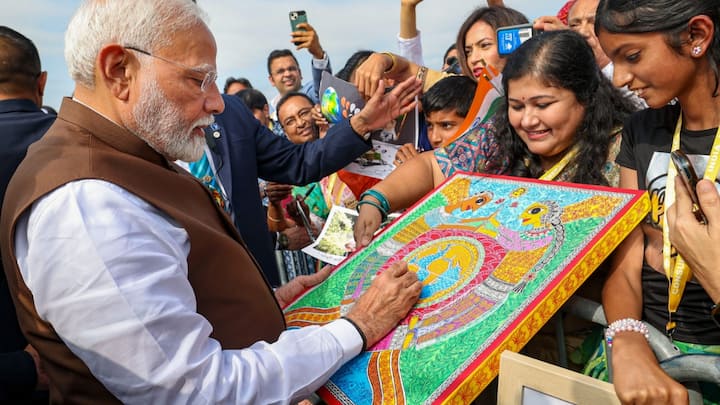 PM Modi was seen waving, shaking hands, clicking pictures, and signing autographs for the community members as they welcomed him. (Image Source: PTI)