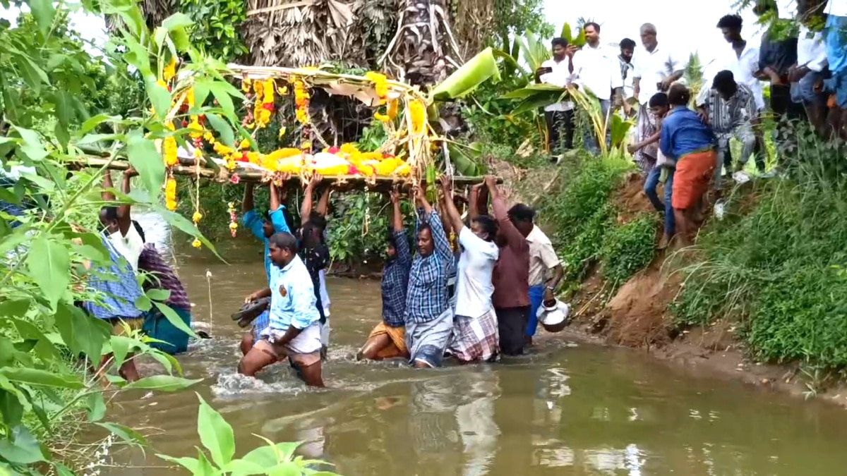 அமைச்சரின் தாயார் ஊரில் அவலம் ; வாய்க்காலில் இறங்கி இறந்தவரின் உடலை எடுத்து செல்லும் மக்கள்