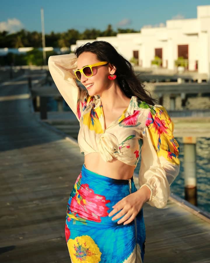 She looks radiant in an off-white floral crop top with bell sleeves, paired perfectly with a matching fitted skirt.