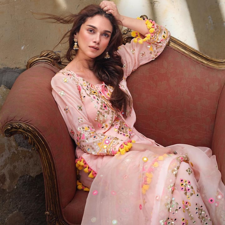 This stunning peach-pink mirror work dress is beautifully complemented by a simple kohl makeup look and nude tones. The outfit features lightweight earrings and messy pleats, while the traditional mirror work detailing in the dupatta enhances her gorgeous personality.