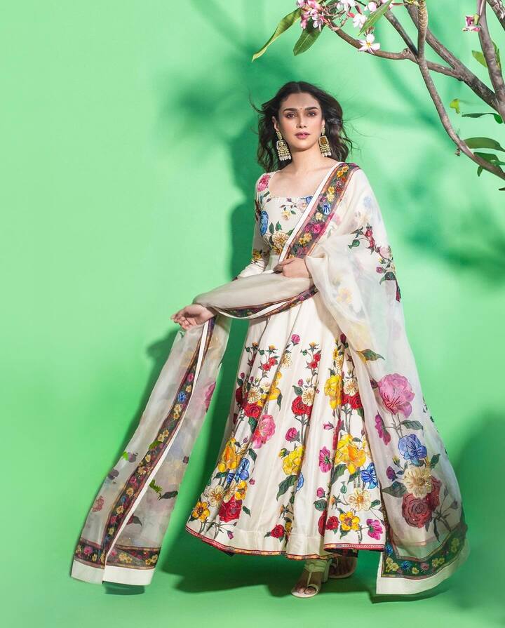 Aditi Rao Hydari looked effortlessly elegant in a simple yet chic white Anarkali suit adorned with delicate floral prints. The soft floral design enhanced her natural charm, while her look was elevated with statement heels, gorgeous heavy earrings, and a classic black bindi that added a touch of traditional grace.