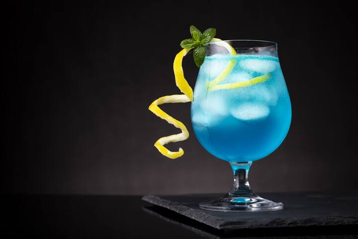 Now place a slice of lemon and mint leaves on top of this glass. Now your Blue Lagoon is ready, you can serve it.