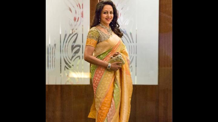 4. Elegant Silk Saree: This elegant flowing silk saree in soft peach, green and gold hues is paired with a heavily embellished blouse. It exudes timeless elegance and sophistication when paired with a statement necklace, clutch and traditional bangle. (Image Source: Instagram/@dreamgirlhemamalini)
