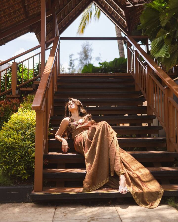 హెయిర్ లీవ్ చేసి.. స్టెప్స్​పై పడుకుని మరీ ఫోటోలకు ఫోజులిచ్చింది. చెవులకు పెద్ద ఝుంకాలు పెట్టుకుని, హైహీల్స్​తో తన శారీ లుక్​ని ఫైనల్ చేసింది. (Images Source : Instagram/Krithi Shetty)