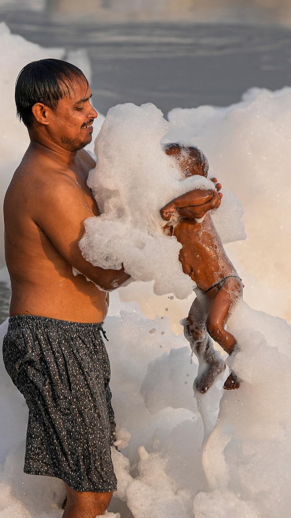 यमुना में सफेद झाग वाले पानी में बच्चों को नहला रहे मां-बाप