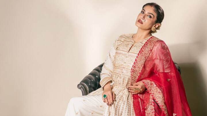 Raveena Tandon stunned in a white Anarkali suit adorned with golden detailing, exuding allure and charm. The contrasting red dupatta, embellished with gold borders, added a vibrant touch.  (Image source: Instagram/ officialraveenatandon)