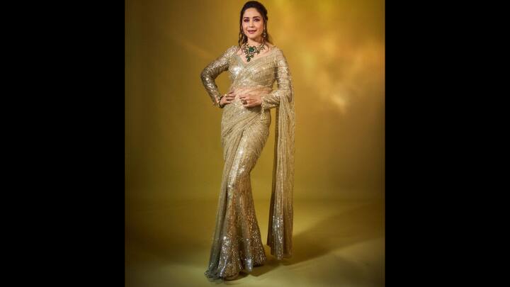 2. Gold Sequined Saree: Madhuri Dixit looks dazzling in her sequined saree attire. The look reflects beautiful festive glow. The gold fabric and styling creates a mesmerising look that's perfect for the evening celebrations of Diwali. (Image Source: Instagram/@madhuridixitnene)