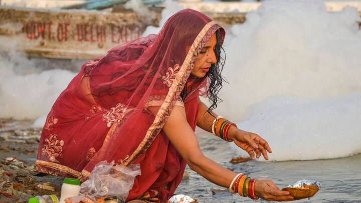 Devotees took a dip in the river Yamuna in Delhi's Kalindi Kunj area which remained covered in a thick layer of toxic foam. Image: PTI