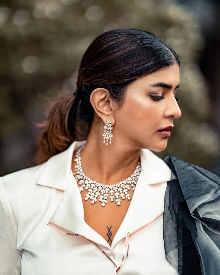 వైట్ క్రాప్ కోట్ వేసుకుని.. దానికి చీరలాంటి లుక్ని తీసుకువచ్చింది మంచువారి అమ్మాయి. సాధారణంగా చీరలకు ఇలా షర్ట్స్, టీషర్ట్స్ వేసుకోవడం ఫ్యాషన్గా మారింది. కానీ ఈ లుక్ వాటికి డిఫరెంట్గా ఉంది. (Images Source : Instagram/Manchu Lakshmi)