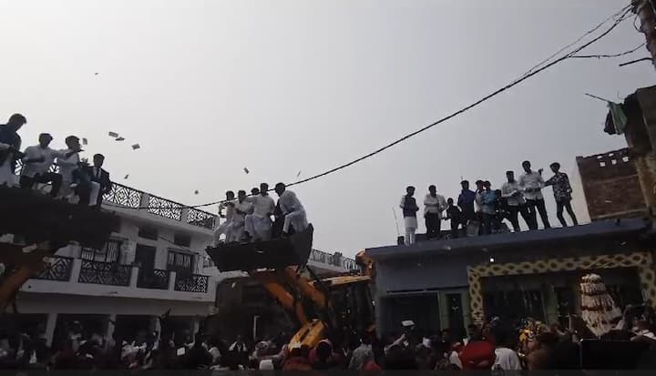 वीडियो में साफ तौर पर देखा जा सकता है कि लड़के के घर वाले जेसीबी में बैठकर और घर की छतों पर चढ़कर 200 और 500 रुपये के नोट हवा में उड़ा रहे है. नोट इस तरह उड़ाया जा रहा था जैसे कि वह कागज हो.