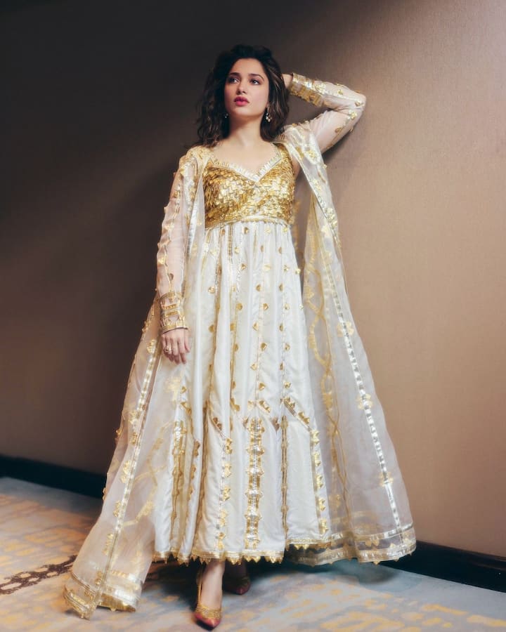 Tamannaah is draped in an ethereal ensemble featuring a white and gold theme, exuding sophistication and grace.