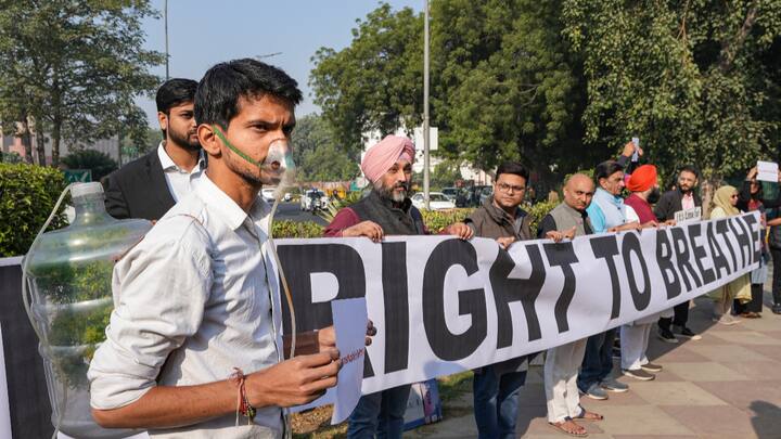 People wearing masks hold a ‘Right To Breathe’ banner near the Parliament House complex.  (Photo: PTI)