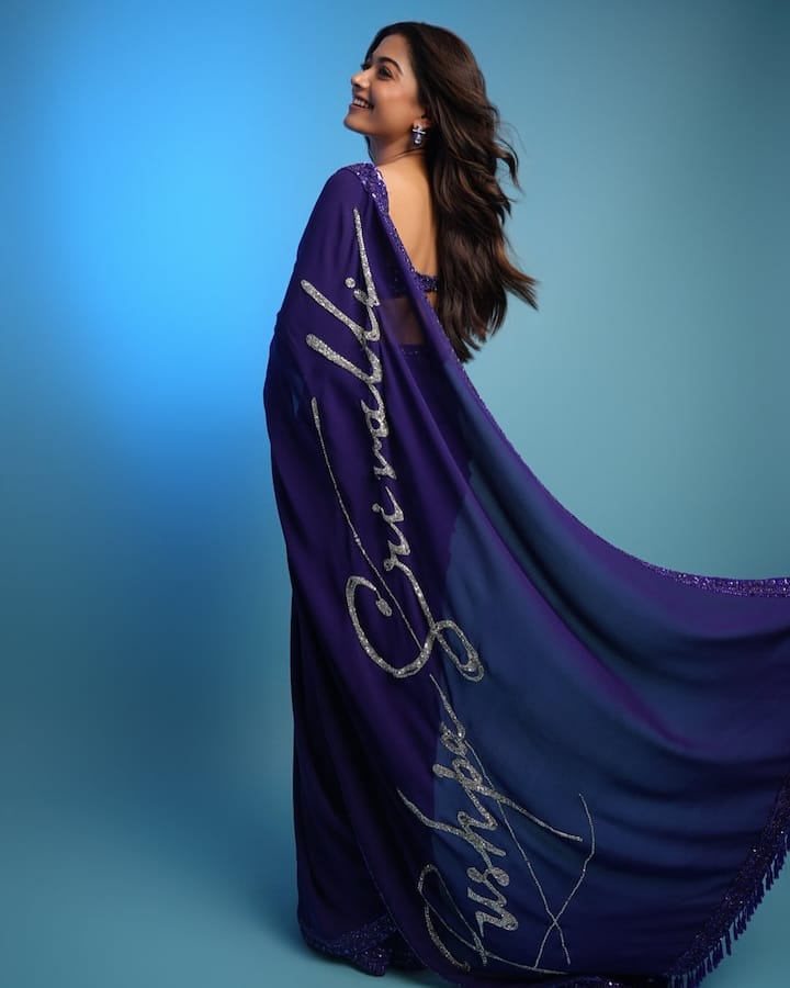 रश्मिका इन तस्वीरों में ब्लू कलर की साड़ी पहने हुए है. जिसके पल्लू पर उन्होंने ‘पुष्पा’ और ’श्रीवल्ली’ लिखावाया हुआ है. एक्ट्रेस ने अपना लुक मैचिंग ज्वेलरी के साथ पूरा किया है.