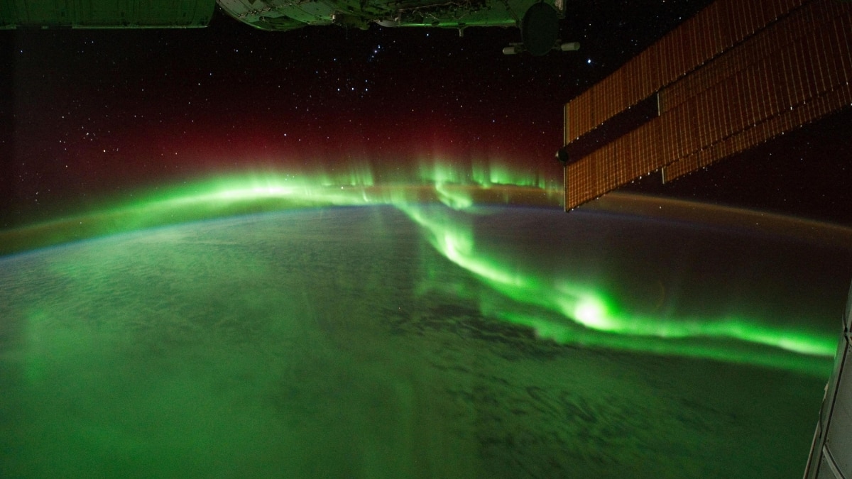 Aurora australis lights up the Indian Ocean as seen from the ISS, with solar panels in the frame. This celestial display highlights Earth’s magnetic connection to the Sun.