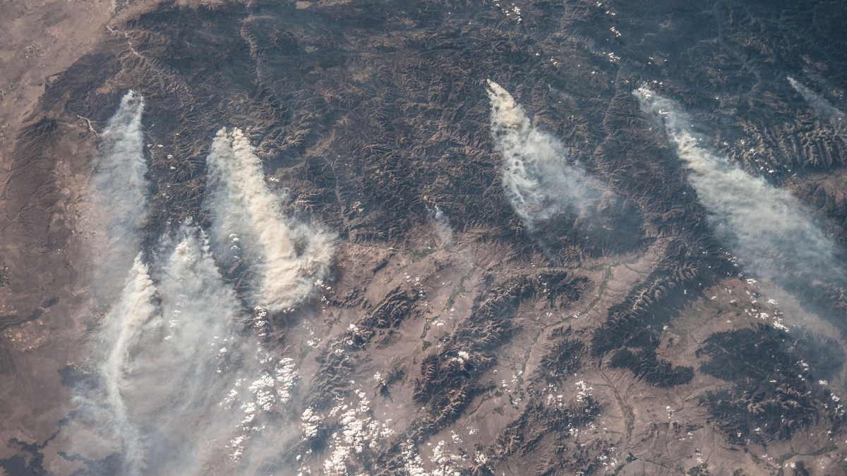 This image captures central Idaho’s forested mountains with smoke plumes from lightning-induced wildfires like Little Queens and Gold Pan, which burned over 53,000 acres. Westerly winds carried the smoke eastward.