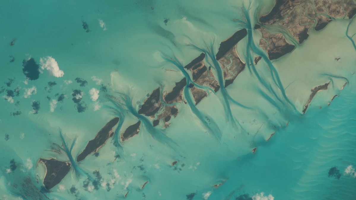 Small cays in the Bahamas display vivid aqua waters and tidal channels. Extending from Great Exuma Island, this picturesque view showcases one of Earth’s most recognizable landmarks.