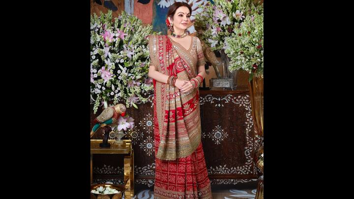 1. Traditional Grace In Red: Nita Ambani stuns in a royal red saree that's adorned with intricate craftsmanship. The traditional draping style with regal accessories exude timeless charm and gives her a sophisticated look. (Image Source: Instagram/@ritikahairstylist)