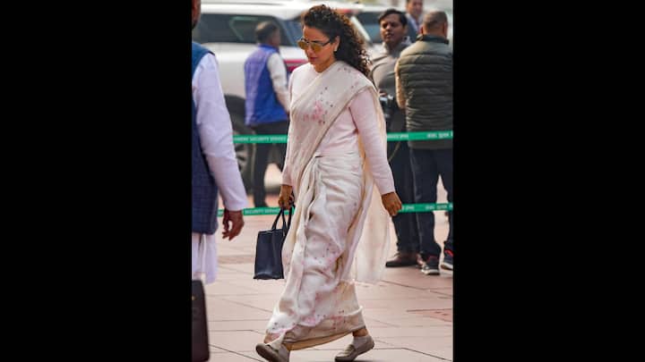 8. Monochromatic Look With A Floral Saree: Kangana Ranaut effortlessly masters simple saree looks, wearing a muted pink saree with floral accents paired with a matching plain sweater. She has accessorised her look with minimal jewellery and a blue bag that adds a vibrant pop to her look. (Image Source: PTI)