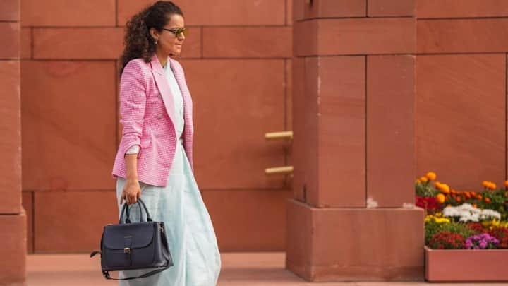 1. Chic Look With Pink Checkered Coat: Kangana Ranaut has worn a pink checkered blazer that adds a chic and modern touch to her outfit. The actress has beautifully blended modernism with simplicity by pairing her light blue saree with the pink blazer. She has accessorised her outfit with brown sunglasses featuring a golden frame. (Image Source: PTI)