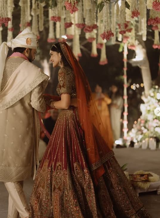 Tanvi wore a maroon colored heavily embellished lehenga in her wedding. She paired it with a matching blouse and had a net dupatta on her head. Tanvi completed her bridal look with Maang Tikka and necklet.