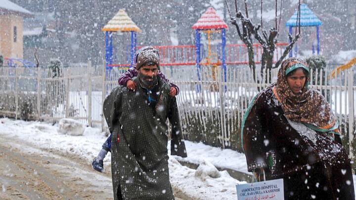 A family walks amid fresh snowfall at Tangmarg area, in Baramulla district, Jammu and Kashmir. Chief Minister Omar Abdullah on Monday said post-snowfall restoration work in the valley was underway in full swing and being closely monitored. (Photo:PTI)