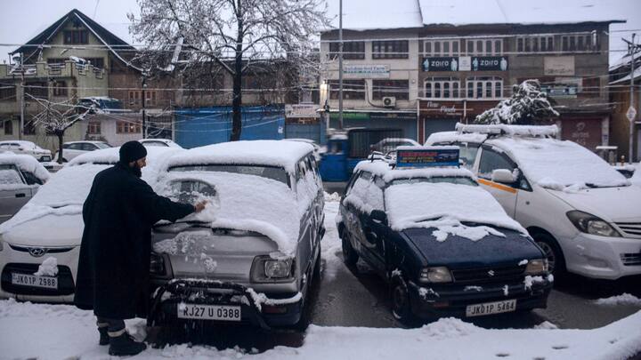 A man clears snow from a van after fresh snowfall, in Srinagar. Srinagar city and some areas in south Kashmir received snow late in the evening. (Photo:PTI)