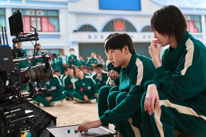 The show’s iconic symbols (circle, triangle, square) are derived from the squid diagram used in the original playground game, reinforcing its thematic importance.