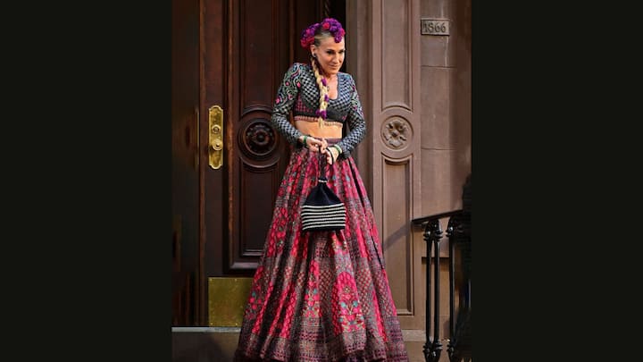 4. Sarah Jessica Parker: Sarah Jessica Parker wore a breathtaking lehenga by Indian designers Falguni and Shane Peacock on the sets of 'And Just Like That'. The red based, multicoloured lehenga made the actress look ethereal. Her lehenga has intricate embroidery and has been crafted from silk threads. (Image Source: Twitter/@RevistaAlaModa)