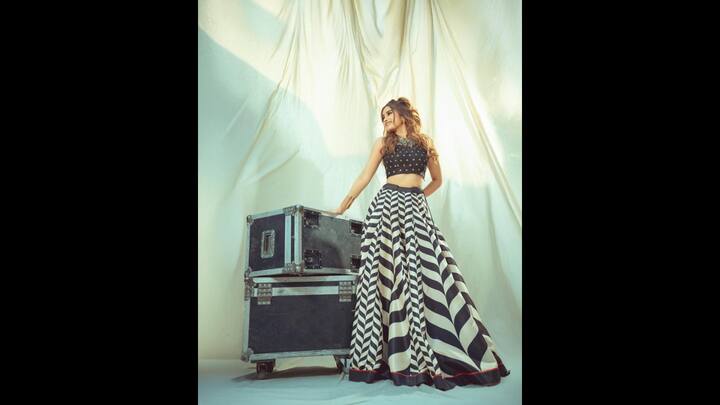7. Black And White Lehega: Rasha Thadani looked stunning in her black and white ethnic lehenga ensemble. She wore a voluminous lehenga adorned with black and white strips, striking red piping, and a broad black border. She complemented her lehenga with a matching cropped sleeveless black blouse, featuring beautiful neckline and intricate gold embroidery. (Image Source: Instagram/@rashathadani)
