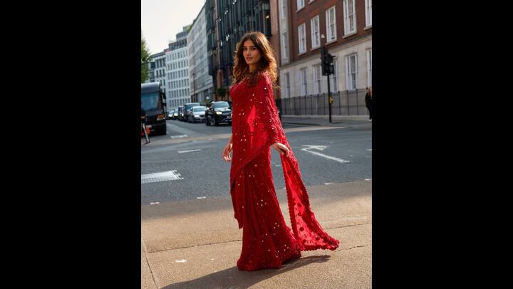 1. Bold Red Saree: Rasha Thadani exudes elegance in a striking bold saree with intricate ruffle designs. The saree is beautifully adorned with delicate mirror work and vibrant red bead embellishments. She paired her look with a heavily embroidered blouse which gave her a captivating look. (Image Source: Instagram/@rashathadani)