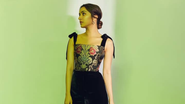 Shraddha Kapoor pulls off a floral crop top with black velvet flared pants, a relaxed yet chic look. A clean low bun rounds up this chic and comfy look — great for fun fashion this Valentine.  (Image Source: Instagram/ shraddhakapoor)