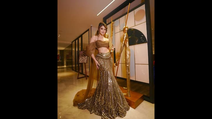 5. Glamorous Golden Look: Urvashi makes a glamorous and luxurious vibe through her outfit. The metal sheen and the structured design affected its figures. He has added his look with a heltenca blouse and a light, net scarf. (Image Source: Instagram/@urvashirautela)