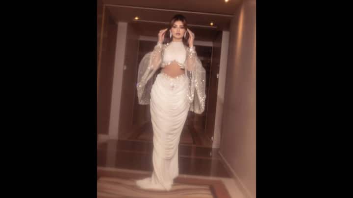 1. Ethereal White Look: Urvashi Rautela looks stunning in her white ensemble. The actress has worn an Indo-Western attire that gives her an angelic look, creating the fusion of modern and classic allure. She has added a shimmery cape to her look that creates a captivating look. (Image Source: Instagram/@urvashirautela)