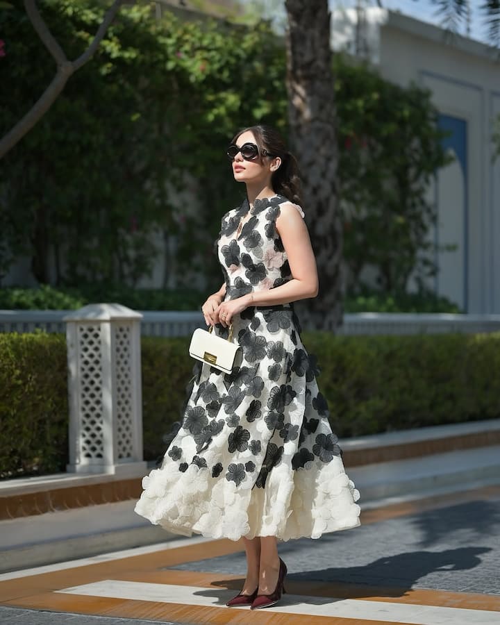 The off-white sleeveless gown featured intricate black and white mesh flowers, adding a delicate yet striking touch to the overall look.