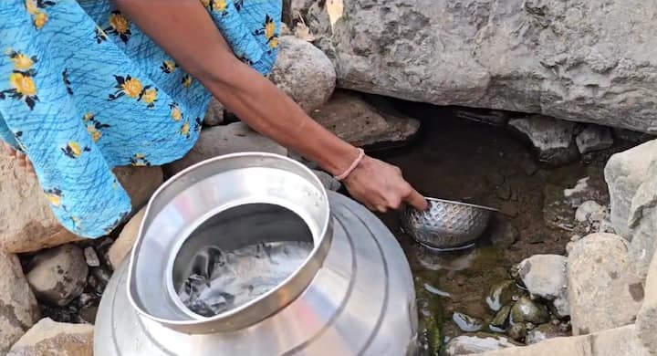 दोनशे फूट खोल दरीत उतरून महिला  झऱ्यातून पाणी भरताना दिसत आहेत.