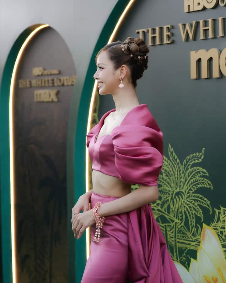 Lisa wowed in a custom-made Louis Vuitton silk dress featuring a sweetheart neckline, petal-like off-the-shoulder sleeves resembling lotus flowers, and a dramatic pleated train.