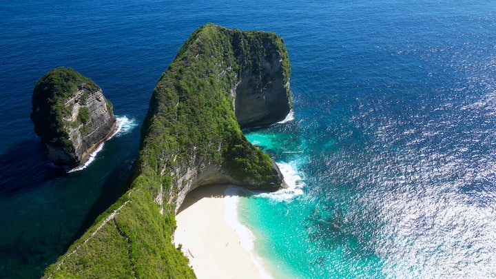 Kelingking Beach, Nusa Penida, Indonesia: Known for its dramatic cliffside views and pristine white sand, Kelingking Beach is a must-visit in Indonesia. The clear waters are ideal for snorkelling, while the secluded setting adds to its charm. Sunsets here create a mesmerising view, perfect for photographs and travellers alike. (Image Source: Canva)