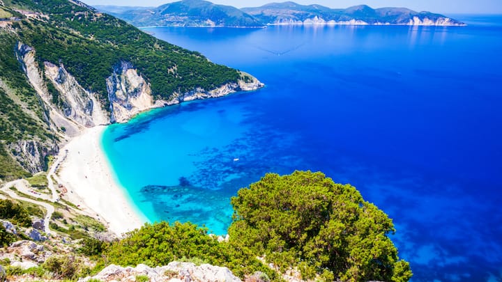 Myrtos Beach, Kefalonia, Greece— Nestled between mountains, Myrtos Beach is a hidden gem in Greece. Its cobalt blue waters invite visitors for a refreshing swim or snorkelling adventure. The people are less visiting here, so this is a great place to relax while enjoying nature's beauty. (Image Source: Canva)