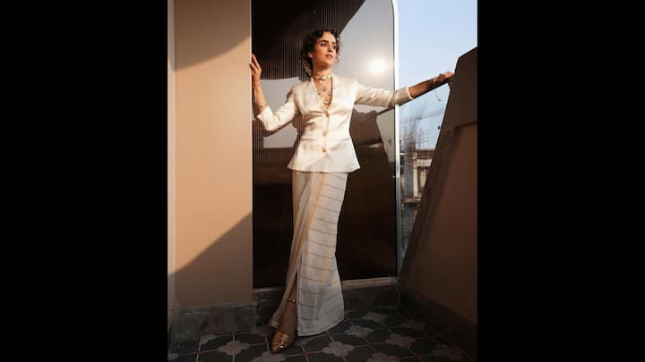 7. Sanya Malhotra: Sanya Malhotra modernised the traditional saree effortlessly by pairing her Kasavu saree with an elegant white blazer. Her blazer featured gold buttons and a plunging neckline. She wore a blouse instead of a blouse with her saree that gave her a bold look. (Image Source: Instagram/@sanyamalhotra_)